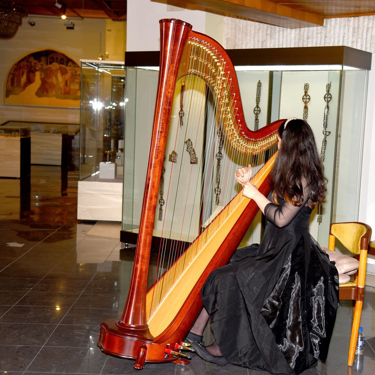 Alexandrina playing harp in a museum-like interior